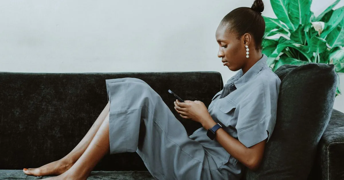 Woman on her sofa applying for quick loans Canada lenders offer on her phone
