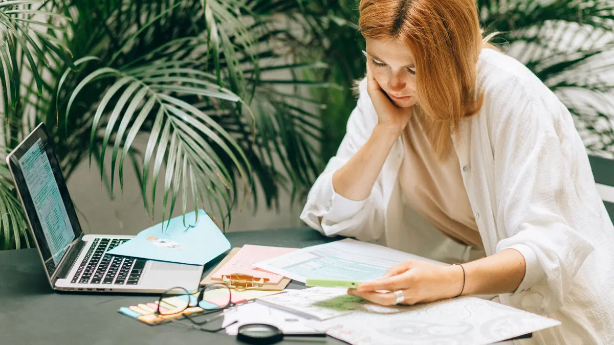 Woman reading her credit report beside her laptop before comparing bad credit quick loans
