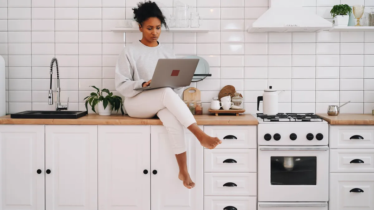 Woman filling in a quick $500 loan application on her laptop in her kitchen