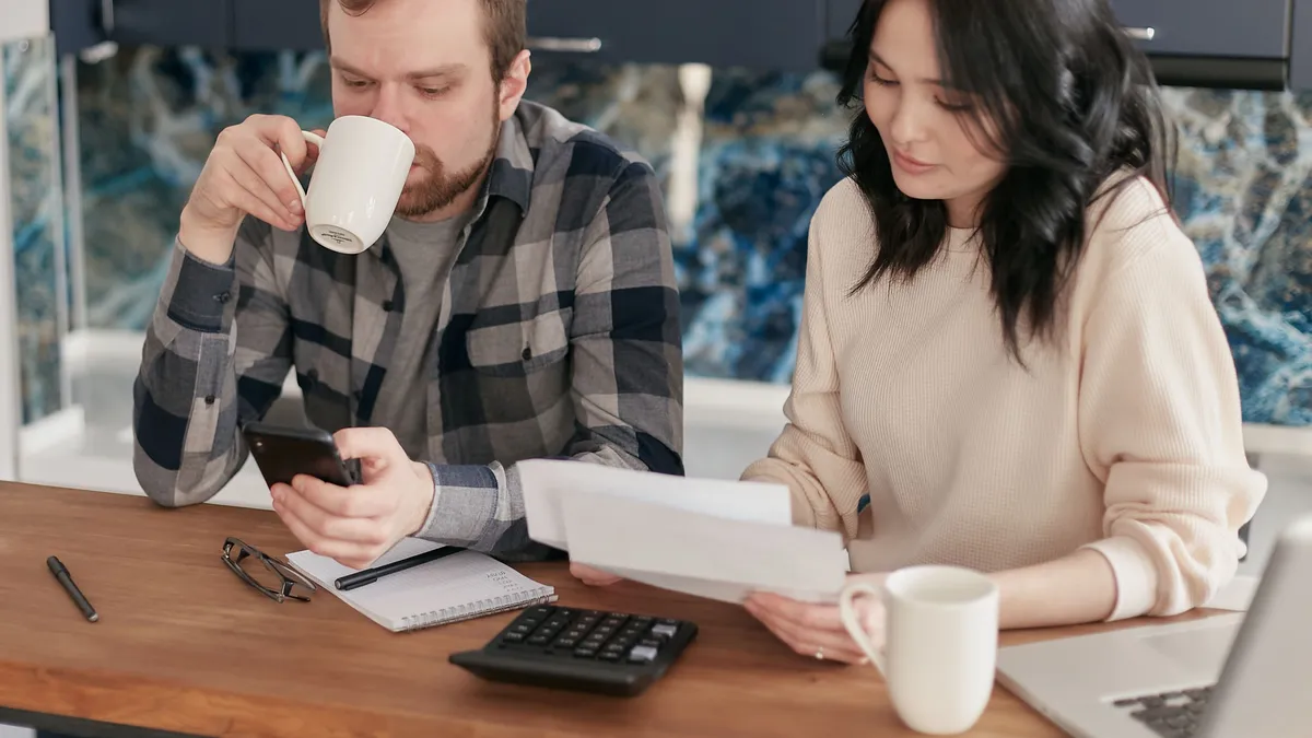 Couple at their kitchen table working out what a $500 loan costs over three and six months with a calculator