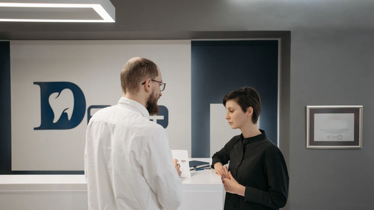 Patient discussing a $500 treatment deposit at a dental clinic reception desk