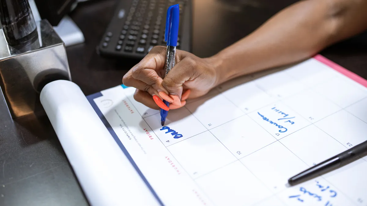 Hand marking the repayment dates for a $500 loan on a desk calendar