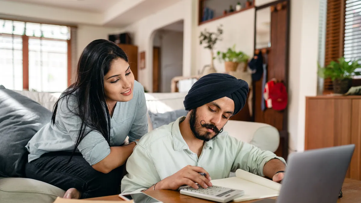 Couple at a coffee table working out which quick cash loans payment fits their budget with a calculator and laptop