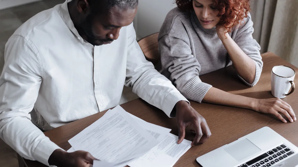 Couple reading the written offer on their quick cash loans at a desk before signing