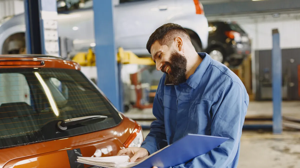 Mechanic on the phone going through a repair estimate in a garage, the kind of bill quick cash loans cover